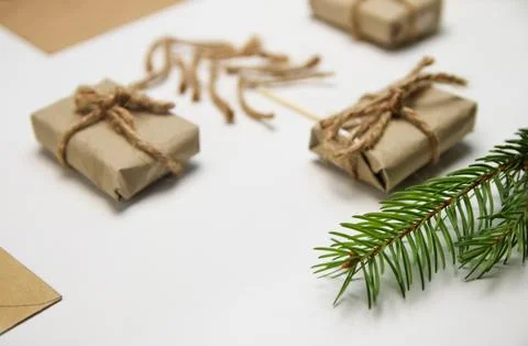 Wrapped small gift boxes with twine rope, craft paper envelopes, and a pine.. Photos