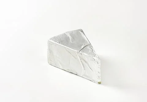 Wrapped triangular cheese slice on foil Stock Photos