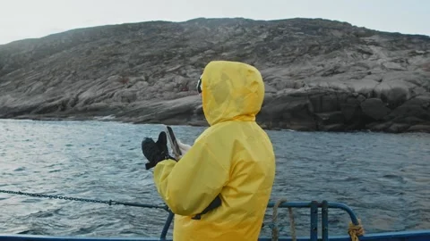 Wrapped in warm clothes and wearing hood, traveler on ship explores cold and Video stock 297582469