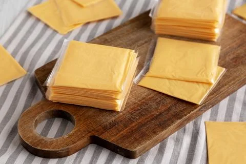 Wrapped Yellow Cheddar Cheese in a Stack on a wooden board, side view. Foto stock
