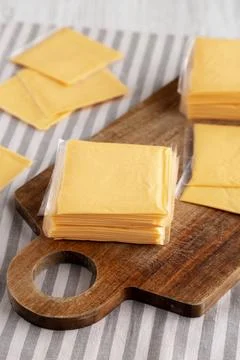 Wrapped Yellow Cheddar Cheese in a Stack on a wooden board, side view. Foto stock