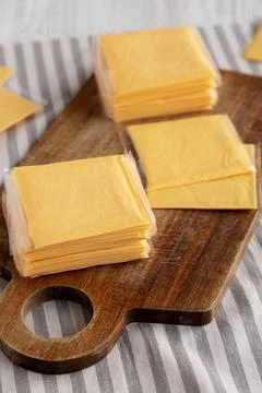 Wrapped Yellow Cheddar Cheese in a Stack on a wooden board, side view. Foto stock