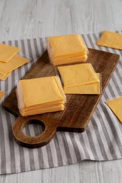 Wrapped Yellow Cheddar Cheese in a Stack on a wooden board, side view. Foto stock