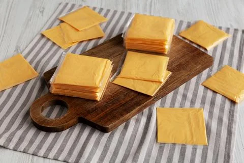 Wrapped Yellow Cheddar Cheese in a Stack on a wooden board, side view. Foto stock