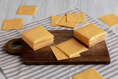 Wrapped Yellow Cheddar Cheese in a Stack on a wooden board, side view. Foto stock