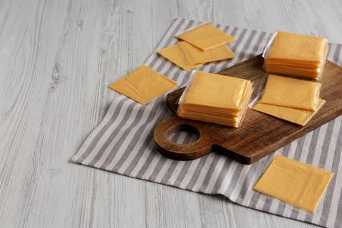 Wrapped Yellow Cheddar Cheese in a Stack on a wooden board, side view. Copy.. Foto stock