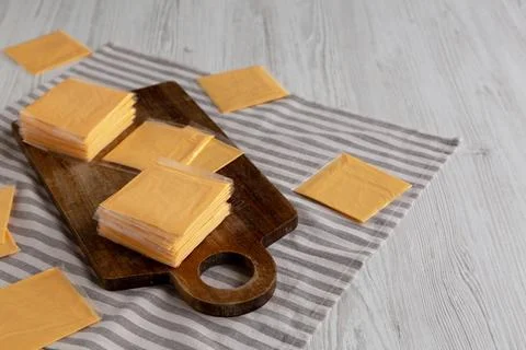 Wrapped Yellow Cheddar Cheese in a Stack on a wooden board, side view. Foto stock