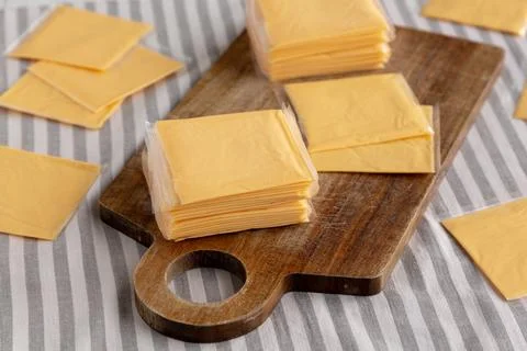 Wrapped Yellow Cheddar Cheese in a Stack on a wooden board, side view. Foto stock