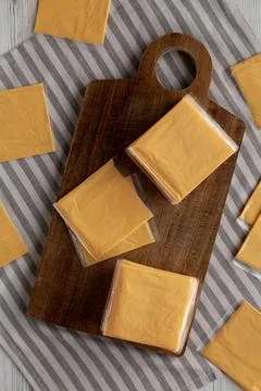 Wrapped Yellow Cheddar Cheese in a Stack on a wooden board, top view. Foto stock