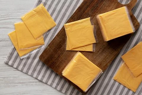 Wrapped Yellow Cheddar Cheese in a Stack on a wooden board, top view. Stock Photos