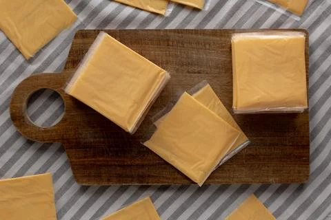 Wrapped Yellow Cheddar Cheese in a Stack on a wooden board, top view. Foto stock