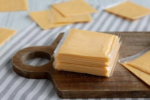 Wrapped Yellow Cheddar Cheese in a Stack on a wooden board, side view. Clos.. Foto stock