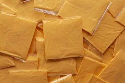 Wrapped Yellow Cheddar Cheese in a Stack on a wooden board, top view. Foto stock