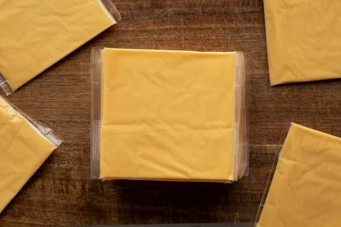 Wrapped Yellow Cheddar Cheese in a Stack on a wooden board, top view. Foto stock