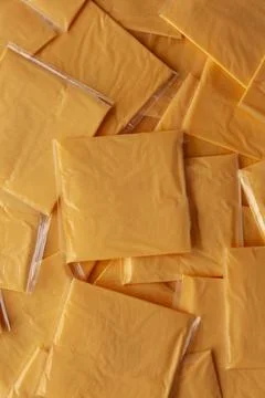 Wrapped Yellow Cheddar Cheese in a Stack on a wooden board, top view. Stock Photos