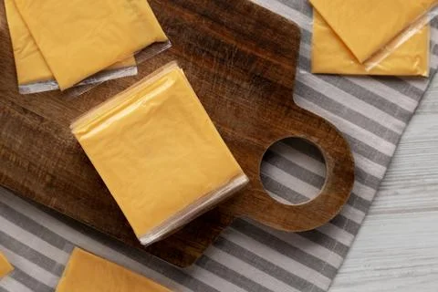Wrapped Yellow Cheddar Cheese in a Stack on a wooden board, top view. Foto stock