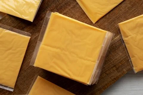 Wrapped Yellow Cheddar Cheese in a Stack on a wooden board, top view. Foto stock