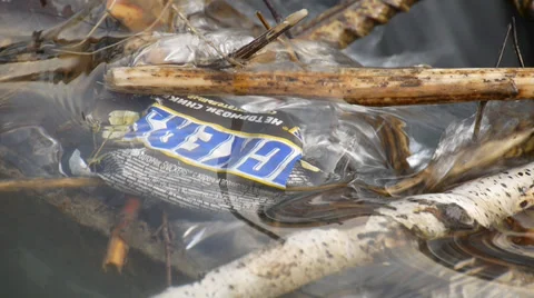 Wrapper of recognizable chocolate bar contaminates water. Snickers Stock Footage 37270289