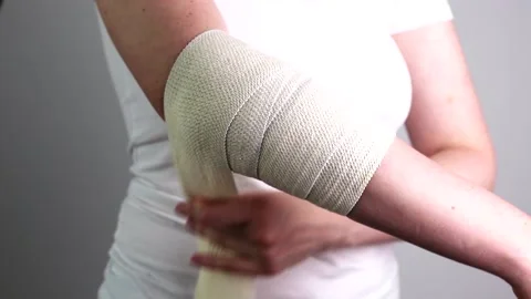 Wrapping applying elastic stretchable bandage on elbow joint trauma, injury Stock Footage 202271407