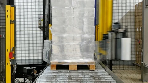 Wrapping boxes on a pallet with plastic in a factory Stock Footage 120468789