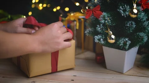 Wrapping up Christmas Gift Besides Small Christmas Tree Stock Footage 96152366