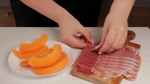 Wrapping prosciutto around melon slices, traditional Italian dish Stock Footage 316676455