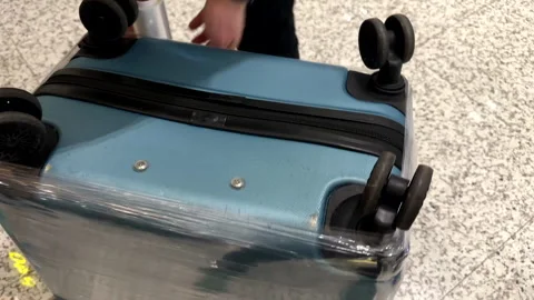 Wrapping suitcase in protective stretch film at airport to protect luggage Video stock 341895265