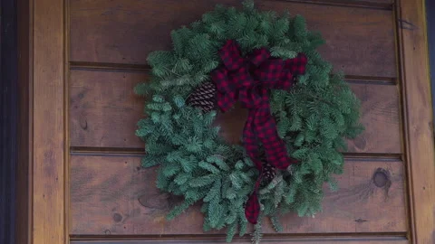 A wreath with pinecones and a red ribbon on the exterior wall of a house Stock Footage 317736571