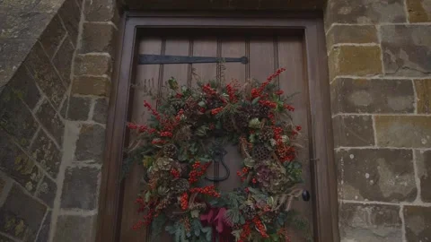 A wreath of red berries and pine needles hangs on a door Stock Footage 302471186