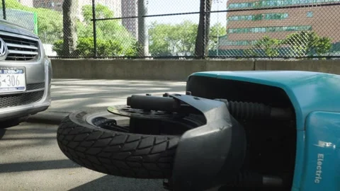The wreck of a crashed and overturned sideways blue scooter motorbike near a Stock Footage 242311400