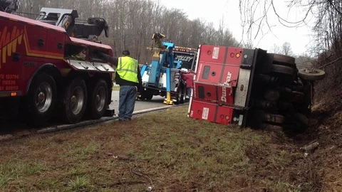 Wrecker team pulling armored car from ditch after wrecking on busy highway Stock Footage 120440690