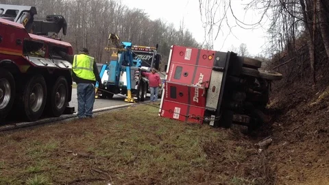 Wrecker team pulling armored car from ditch after wrecking on busy highway Stock Footage 120440695