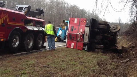 Wrecker team pulling armored car from ditch after wrecking on busy highway Stock Footage 120440698