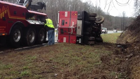Wrecker team pulling armored car from ditch after wrecking on busy highway Stock Footage 120440702