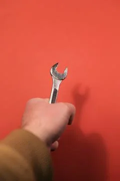 Wrench in hand on a red background. Stock Photos