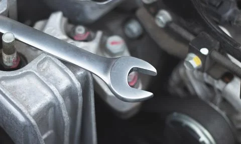The wrench lies on the car engine in the engine compartment. Stock Photos