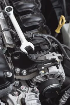 The wrench lies on the car engine in the engine compartment. Stock Photos
