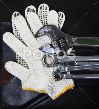 Wrenches spanners plumbing and mechanic glove on dark metal background Stock Photos