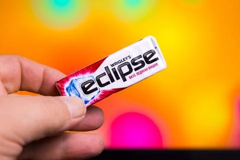Wrigley's Eclipse gum package held in hand with blurry colorful background Stock Photos