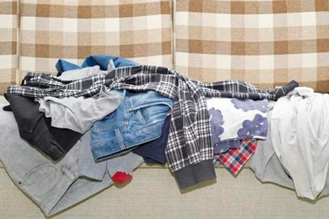 Wrinkled clothes lying on sofa Stock Photos