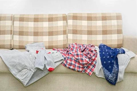 Wrinkled clothes lying on sofa Stock Photos