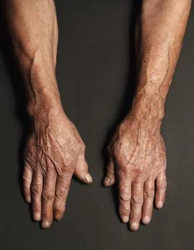 Wrinkled hands of an elderly man on a table close-up on a black Stock Photos