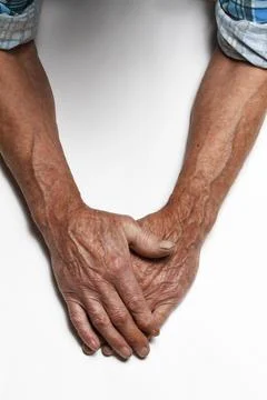 Wrinkled hands of an elderly man on a table close-up on a white Stock Photos
