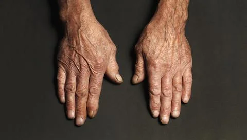 Wrinkled hands of an elderly man on a table close-up on a black Foto stock