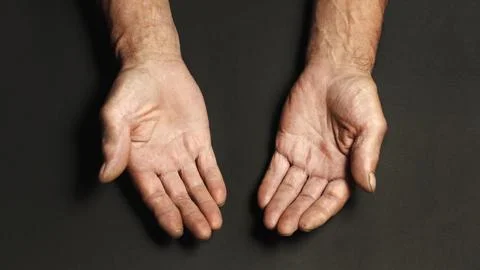 Wrinkled hands of an elderly man on a table close-up on a black Stock Photos