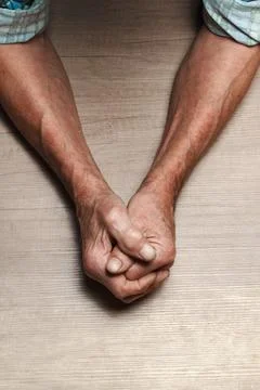 Wrinkled hands of an elderly man on a table close-up on a wooden Stock-Fotos