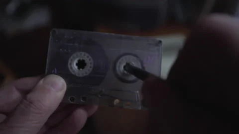 Wrinkled hands rewind tape in outdated cassette with music Stockbeeldmateriaal 239757591