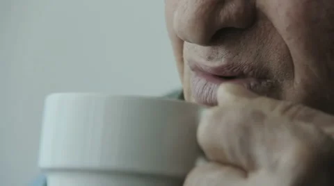Wrinkled old man drinking a cup of hot coffee or tea: thoughtful elderly man Stock Footage 48059465