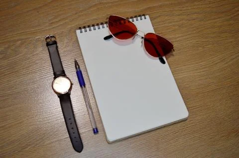 Wrist Watch, notebook, pen and glasses on wooden background Stock Photos