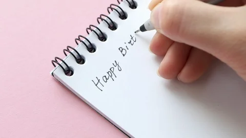 Write Happy Birthday on white notepad paper. Female hand Stock Footage 129198539